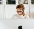 serious lady talking on cellphone while sitting near computer